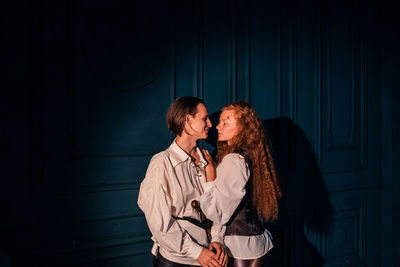 Young couple standing against wall at night