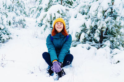 Portrait of young woman skiing on snow covered field