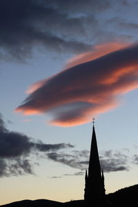 Silhouette steeple of church against cloudy sky during sunset