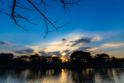 Silhouette trees by lake against sky during sunset