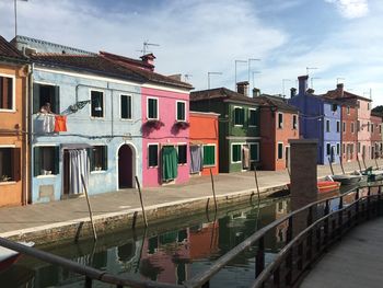 Houses by canal against sky in city