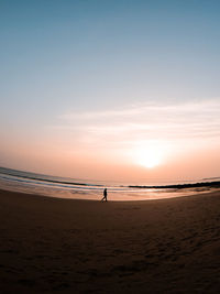 Silhouette people on beach against sky during sunset