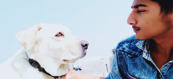 Close-up of teenage boy with dog against sky