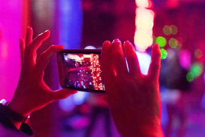 Cropped hand of person taking picture of illuminated lighting