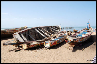 Boats moored on beach against clear sky