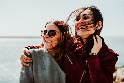 Smiling women looking away against sky