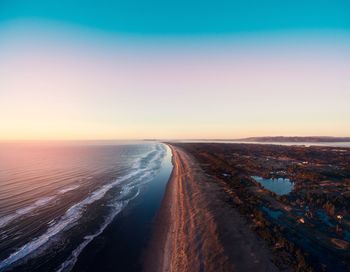 Road by sea against clear sky during sunset