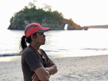 Side view of thoughtful man standing at beach during sunset