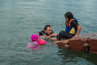 Rear view of mother and daughter in sea