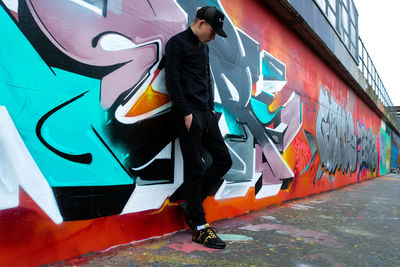 Full length of man standing on graffiti in city