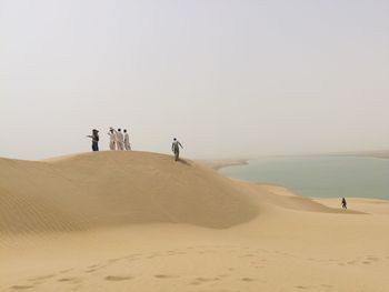 People at desert against clear sky