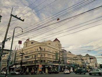 Cars on city street by buildings against sky