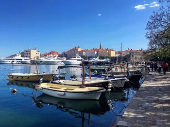 Boats moored at harbor against clear blue sky