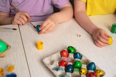 Children's hands that paint quail eggs for easter. preparing for a happy easter holiday