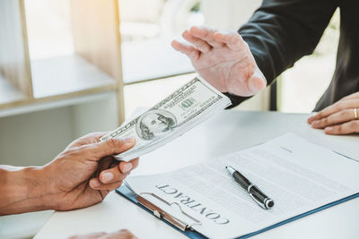 Midsection of man holding paper at table