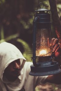 A man lighting an oil lamp in a forest