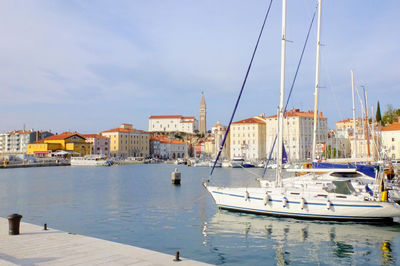 Boats at harbor in piran against sky