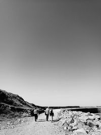 People walking on mountain against clear sky
