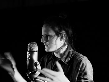Close-up of singer singing in darkroom