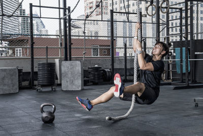 Man training with ropes at rooftop gym in bangkok