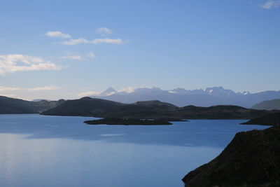 Scenic view of sea and mountains against blue sky