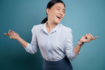 Smiling young woman standing against blue background