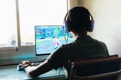 Boy playing game in computer at home