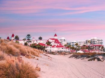 Buildings at beach against sky during sunset