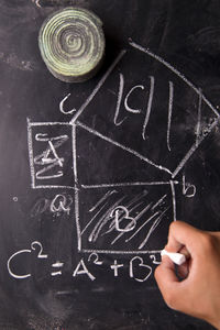 Cropped hand of person writing on blackboard