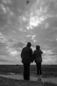 Couple standing on land against cloudy sky