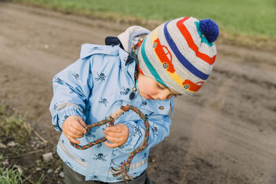 High angle view of boy holding hat on field