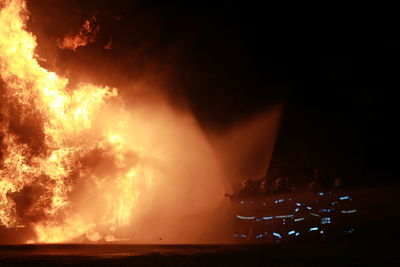 Firefighters spraying water on fire at night