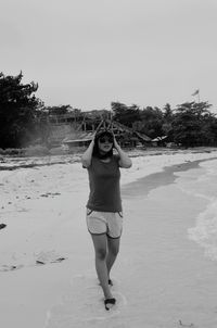 Portrait of young woman standing at sandy beach