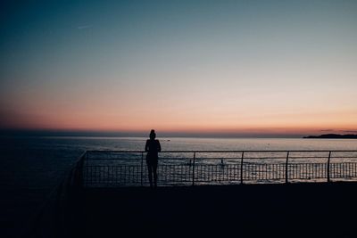 Silhouette people standing on beach against sky during sunset