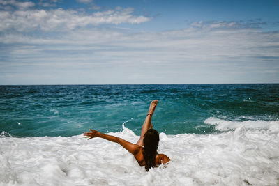 Rear view of woman in sea against sky