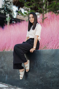Portrait of young woman sitting on retaining wall