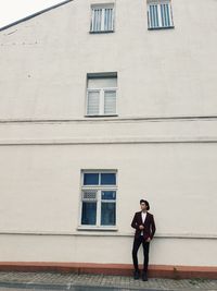 Full length of young woman standing against building