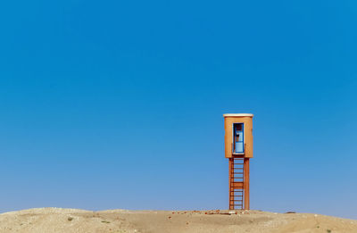 Lifeguard hut at beach against clear blue sky