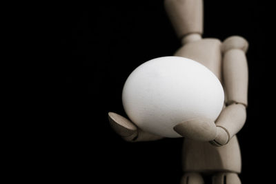 Close-up of hand holding apple against black background