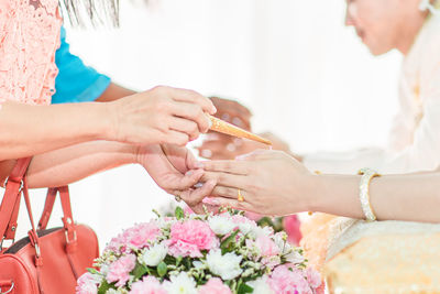 Cropped hands of women performing rituals with bride and groom during wedding