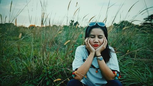 Young woman sitting on grass in field