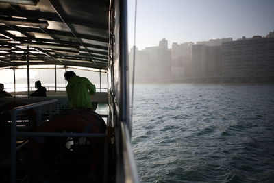 Rear view of men sitting passenger craft on sea