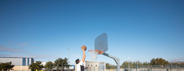 Man playing basketball against sky