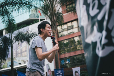 Full length of happy man standing against building in city