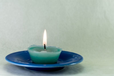 Close-up of illuminated candle against white background