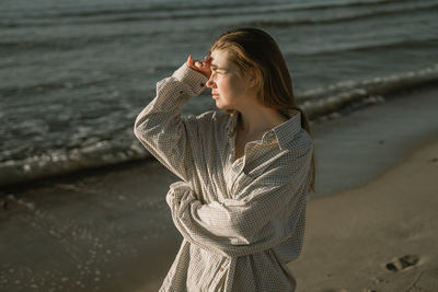 Young woman looking away while standing on beach