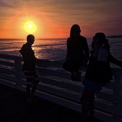 Silhouette of woman looking at sea during sunset