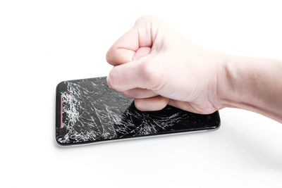 Close-up of hand holding smart phone over white background
