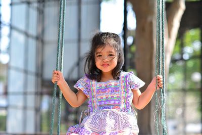 Portrait of cute girl sitting on swing at playground