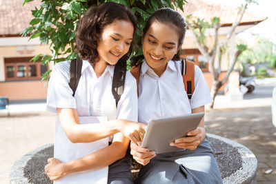 Smiling friends using digital tablet